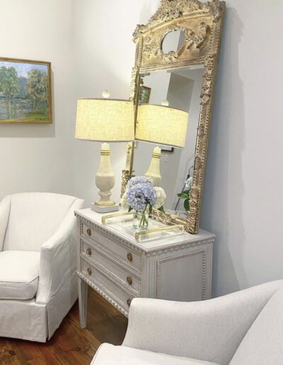 A white chair and a mirror in a room.