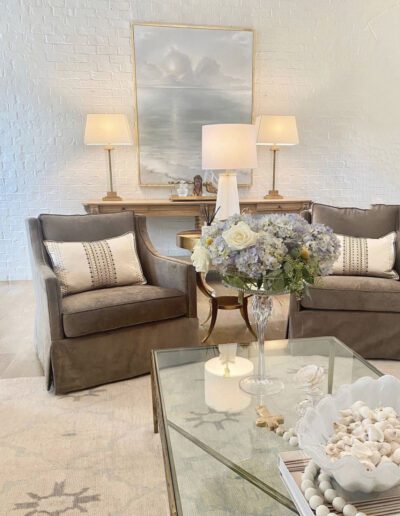 A living room with white furniture and a glass coffee table.