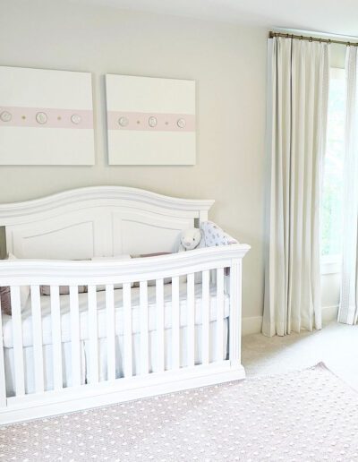 A baby's nursery with a white crib and pink polka dot rug.