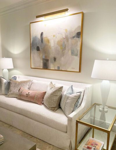 A white couch in a living room with a painting on the wall.