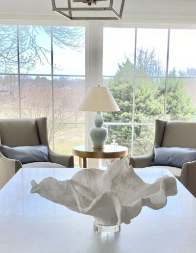 A dining room with a white table and chairs in front of a window.